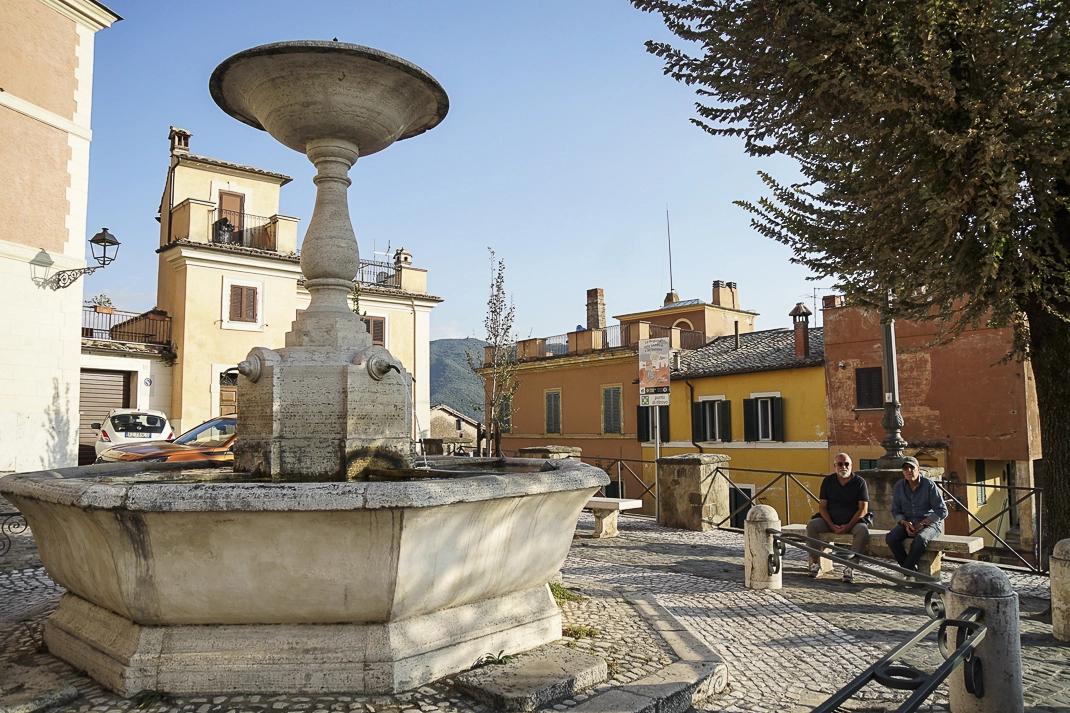 uomini seduti in una piazza con una fontana