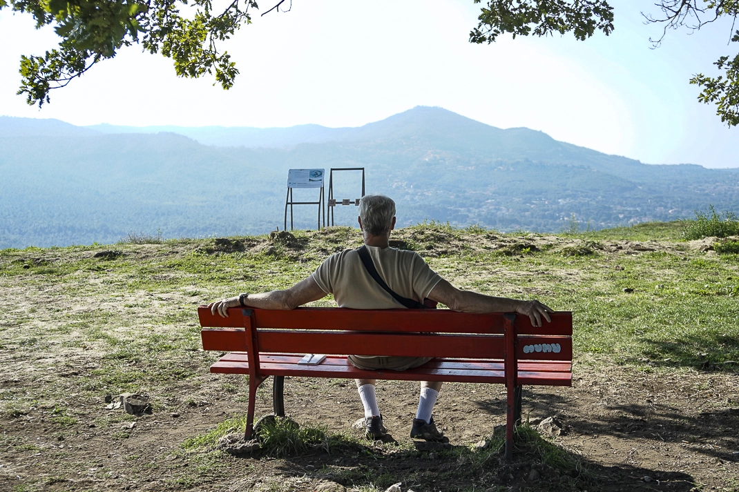 Un uomo seduto in una panchina ammira il panorama.
